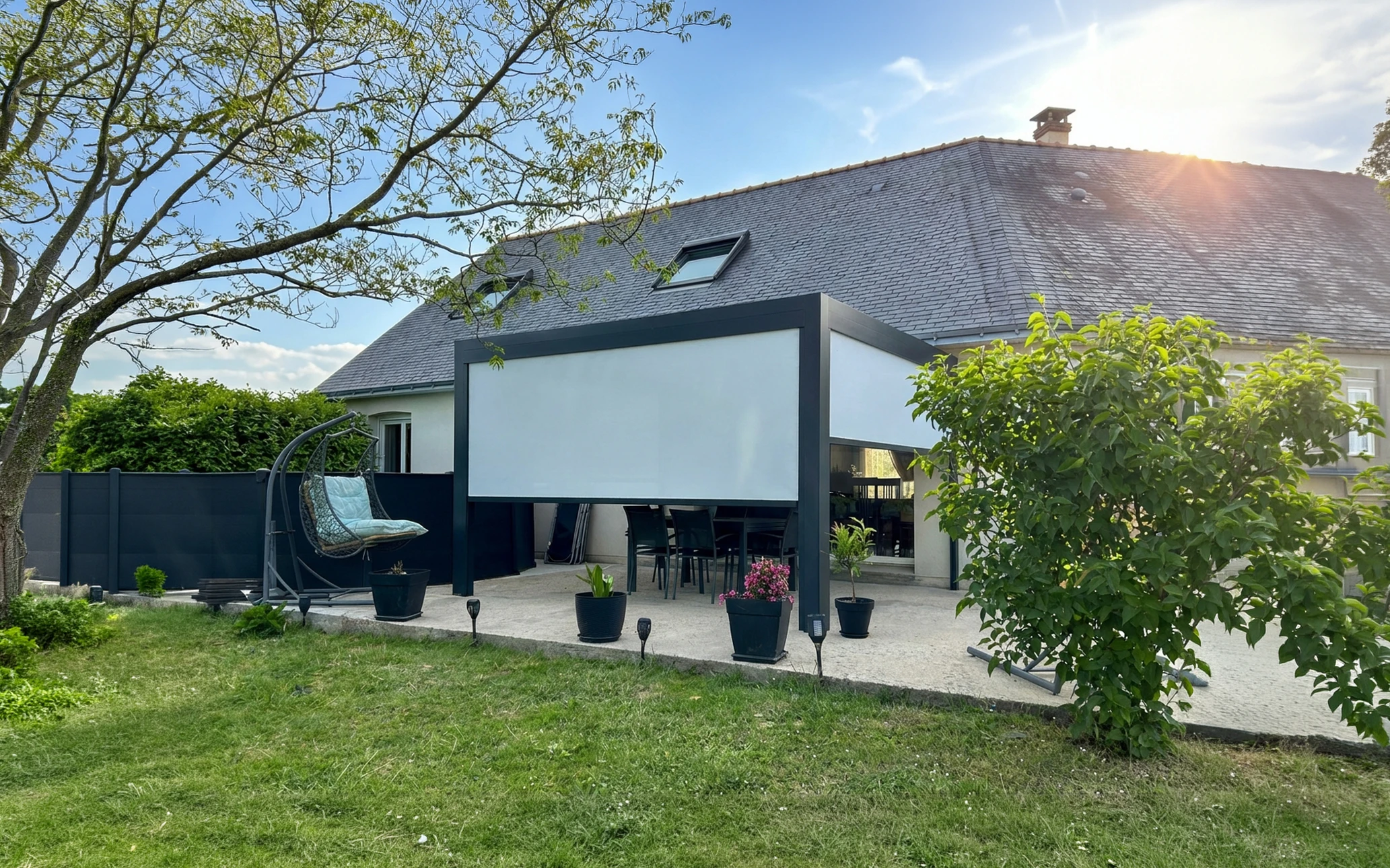 Terrasse couverte par une pergola bioclimatique aluminium anthracite, équipée d'une toile screen extérieure déployée en façade