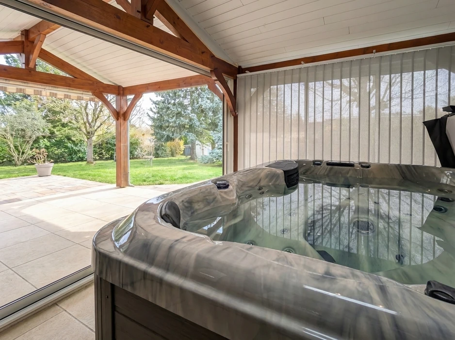 Jacuzzi/spa encastré sous un abri de jardin couvert en bois massif avec charpente apparente et toit à pignon