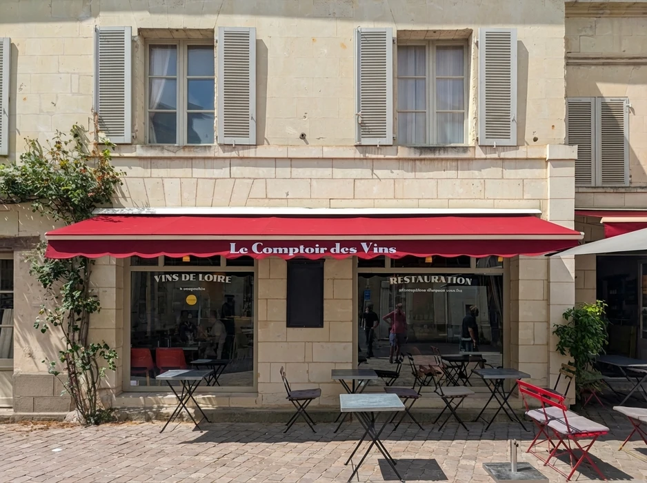 Façade d'un bar à vins français "Le Comptoir des Vins", terrasse extérieure avec tables et chaises bistrot en métal noir