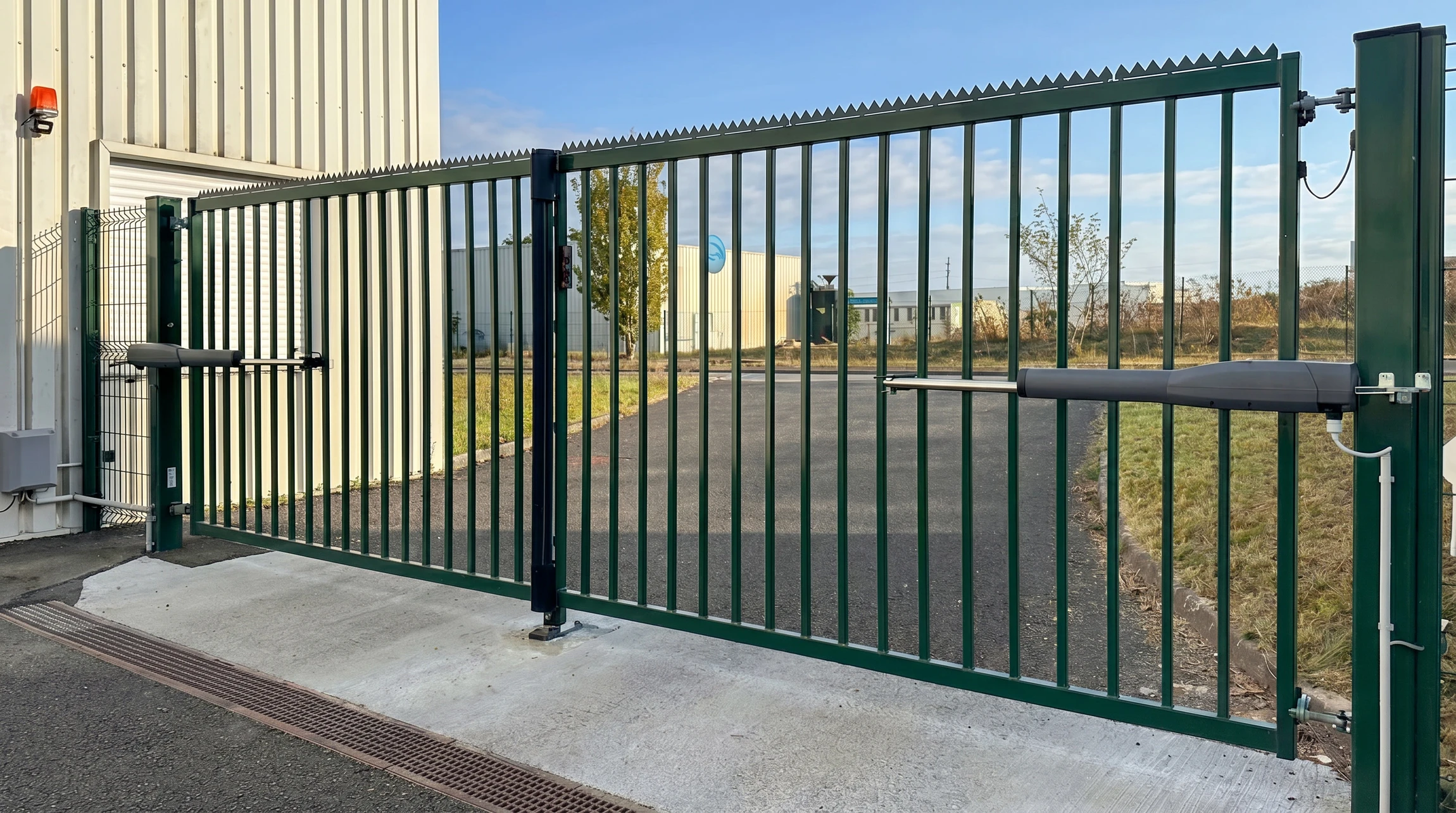 Façade commerciale avec rideau métallique fermé en aluminium laqué beige, installé dans une structure moderne à colonnes blanches