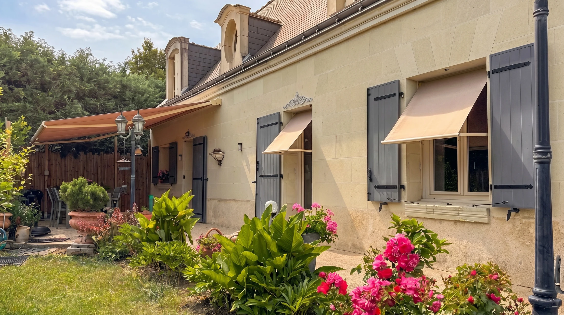 Photographie réaliste d'une maison résidentielle avec des éléments de menuiserie et domotique visibles : fenêtres en PVC ou aluminium de qualité, volets motorisés fermés partiellement, une pergola bioclimatique ou un brise-soleil installé sur la façade, et si possible une porte d'entrée moderne. La maison doit être bien entretenue, photographiée en lumière naturelle du jour, avec un ciel dégagé et du verdure alentour pour un aspect accueillant et professionnel.